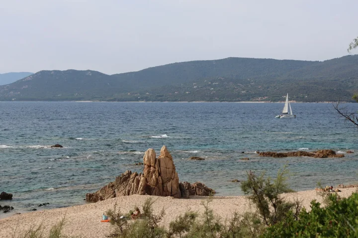Voilier longeant la côte rocheuse de Corse